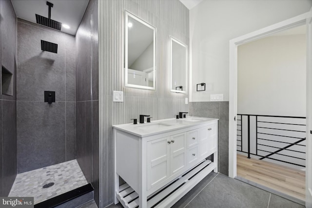 bathroom with hardwood / wood-style floors, vanity, a tile shower, and lofted ceiling