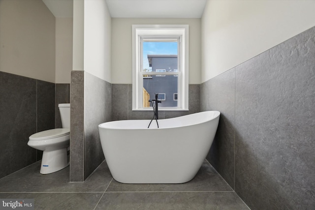 bathroom with toilet, tile walls, tile patterned flooring, and a bathing tub