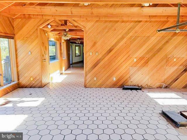 spare room featuring plenty of natural light, wood walls, and beam ceiling