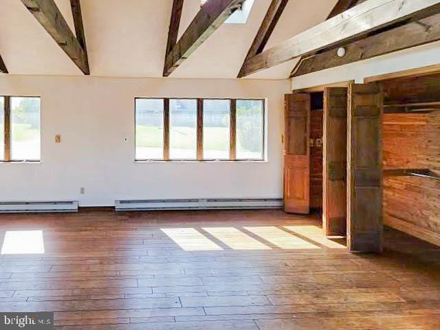 empty room with baseboard heating, hardwood / wood-style flooring, and beamed ceiling