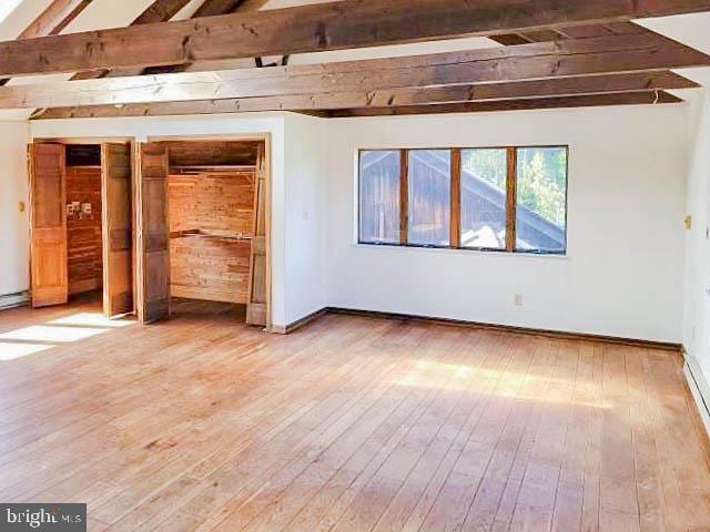 interior space with hardwood / wood-style floors and vaulted ceiling with beams