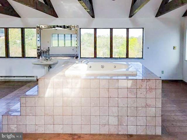 bathroom featuring a baseboard heating unit, hardwood / wood-style floors, tiled tub, and vaulted ceiling