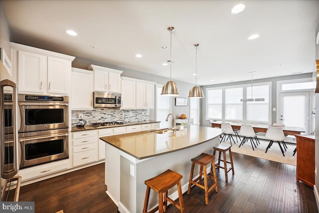 kitchen featuring pendant lighting, dark hardwood / wood-style flooring, white cabinets, and stainless steel appliances