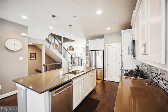 kitchen featuring sink, pendant lighting, a kitchen island with sink, white cabinets, and appliances with stainless steel finishes