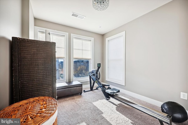 exercise room featuring a notable chandelier and light carpet