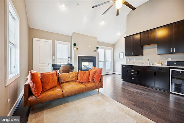 living room featuring ceiling fan, sink, beverage cooler, light hardwood / wood-style flooring, and high vaulted ceiling