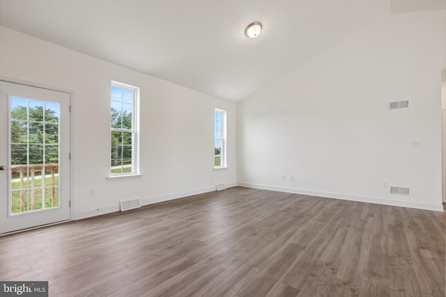 spare room featuring a wealth of natural light, wood-type flooring, and vaulted ceiling