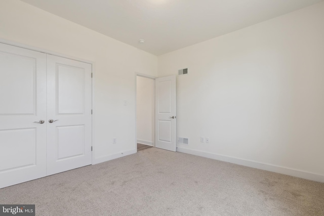 unfurnished bedroom featuring light colored carpet and a closet