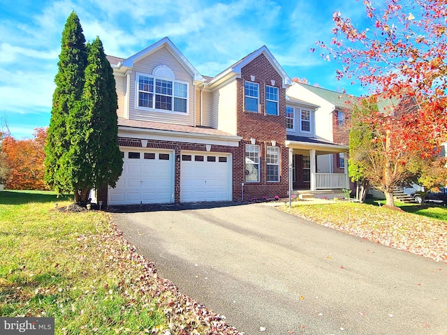 view of property featuring a garage, a front yard, and covered porch