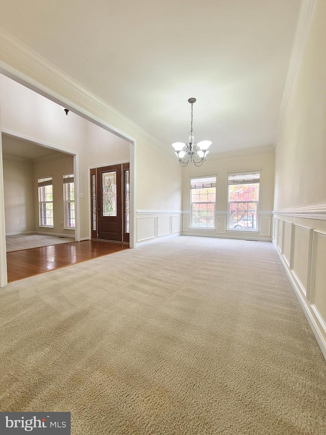 interior space with a chandelier, carpet floors, and crown molding