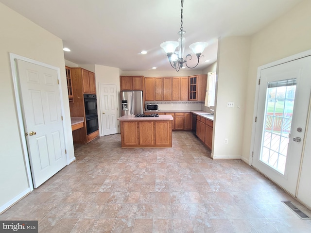 kitchen featuring black appliances, a notable chandelier, pendant lighting, sink, and a center island