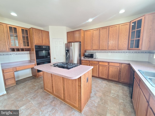 kitchen featuring black appliances, tasteful backsplash, a kitchen island, and sink