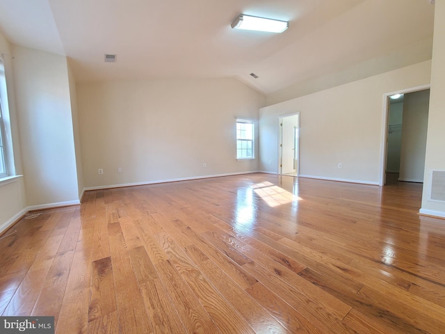 empty room with light wood-type flooring and vaulted ceiling