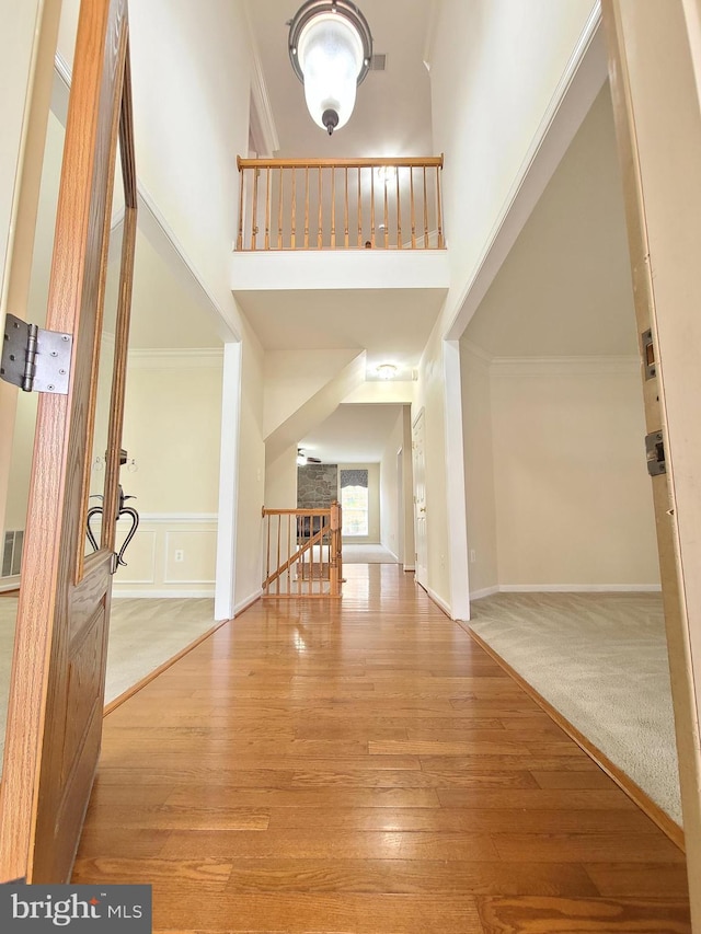 carpeted foyer entrance featuring crown molding and a towering ceiling