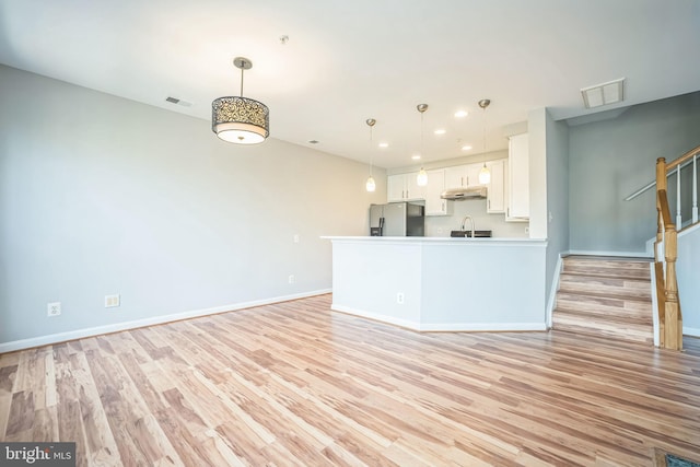 kitchen with sink, light wood-type flooring, white cabinetry, and stainless steel refrigerator with ice dispenser