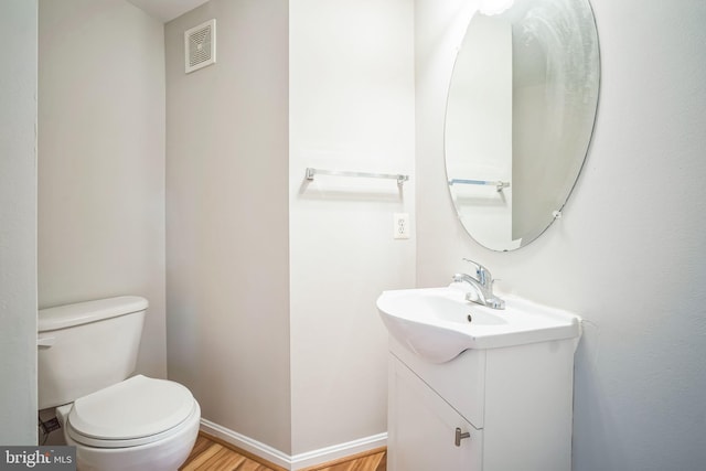 bathroom with hardwood / wood-style floors, vanity, and toilet