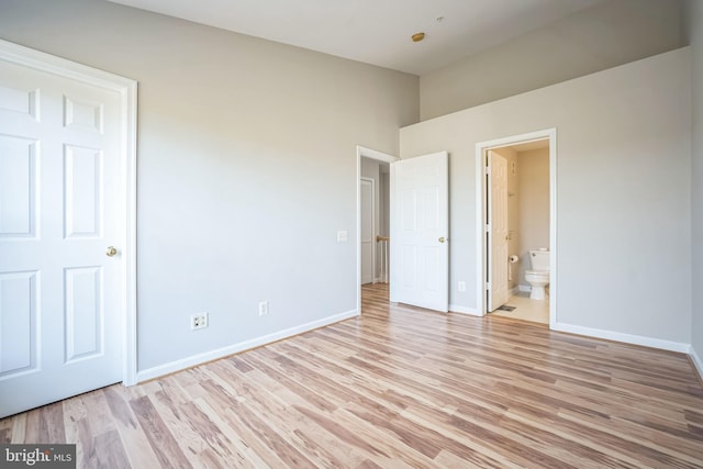 unfurnished bedroom with light wood-type flooring and connected bathroom