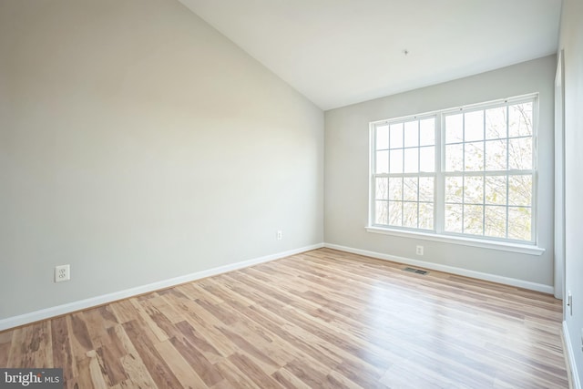 spare room featuring light wood-type flooring and lofted ceiling