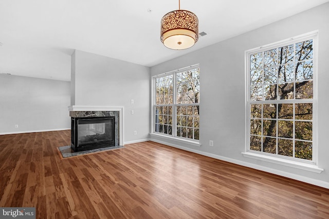 unfurnished living room featuring hardwood / wood-style flooring, lofted ceiling, and a premium fireplace