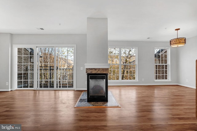 unfurnished living room featuring a multi sided fireplace and hardwood / wood-style flooring