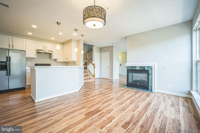 kitchen featuring stainless steel fridge, light hardwood / wood-style flooring, white cabinetry, and hanging light fixtures