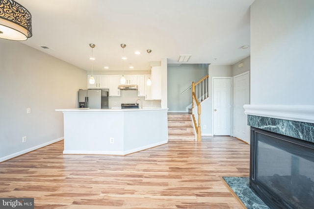 kitchen featuring stainless steel fridge, sink, decorative light fixtures, light hardwood / wood-style flooring, and white cabinets