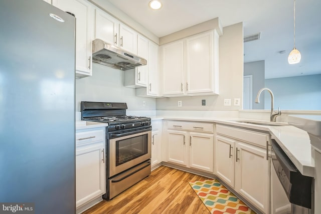 kitchen with white cabinets, sink, decorative light fixtures, light hardwood / wood-style floors, and stainless steel appliances