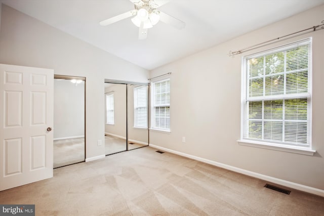 unfurnished bedroom with ceiling fan, multiple windows, two closets, and light colored carpet