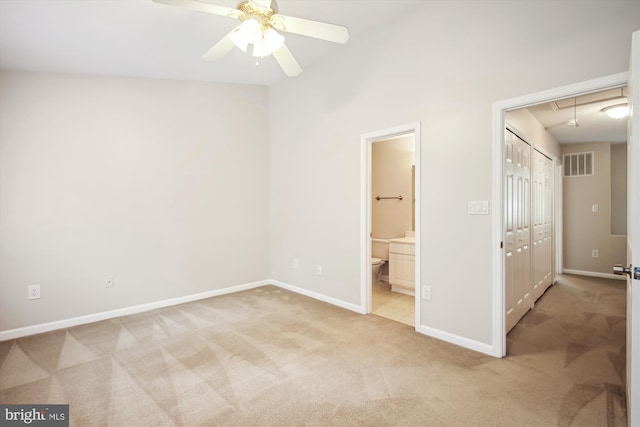 unfurnished bedroom featuring ceiling fan, light colored carpet, ensuite bath, and a closet