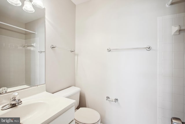 bathroom featuring tiled shower, vanity, and toilet