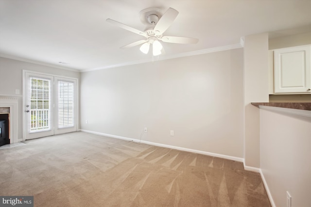 unfurnished living room with a fireplace, ceiling fan, light colored carpet, and crown molding