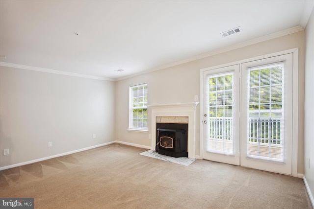 unfurnished living room with a wealth of natural light, light carpet, a wood stove, and ornamental molding