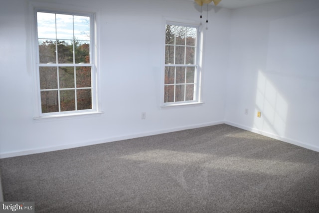 carpeted empty room with ceiling fan and plenty of natural light