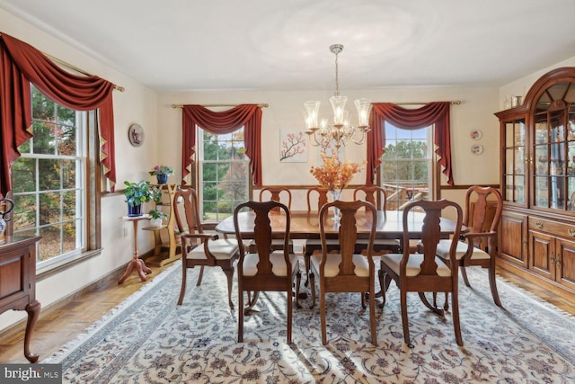 dining area featuring a wealth of natural light, light parquet floors, and a notable chandelier