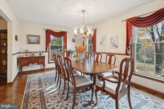 dining area featuring a notable chandelier and dark parquet flooring