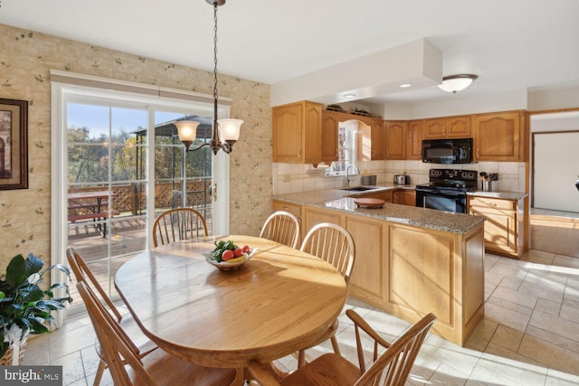 kitchen featuring kitchen peninsula, backsplash, sink, black appliances, and pendant lighting