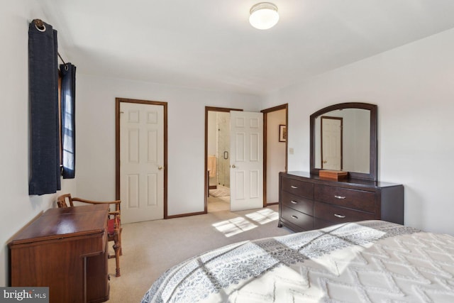 bedroom with ensuite bathroom and light carpet