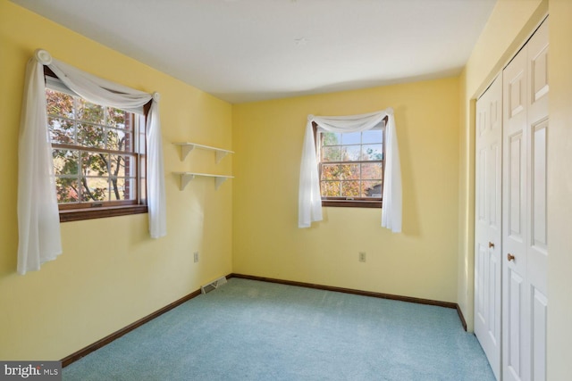 bedroom with light colored carpet, multiple windows, and a closet