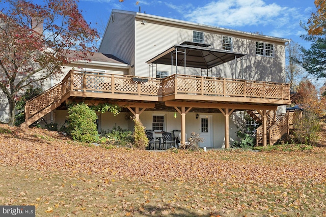 back of property featuring a gazebo and a deck