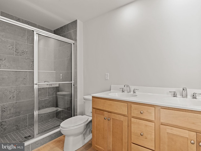 bathroom featuring wood-type flooring, vanity, toilet, and walk in shower