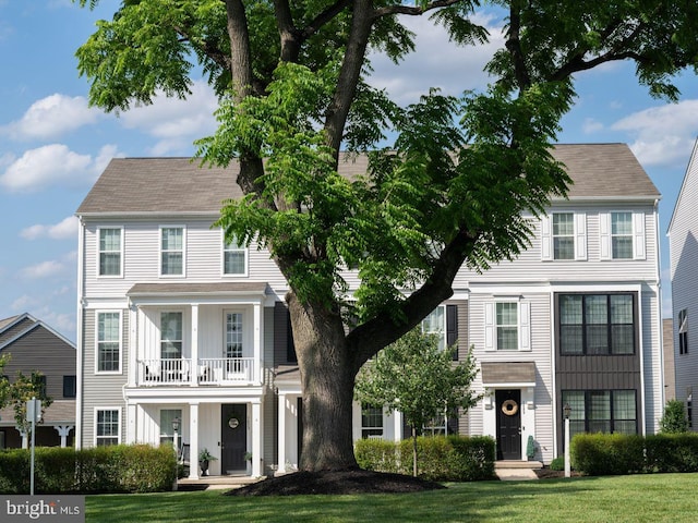 colonial house with a balcony and a front lawn