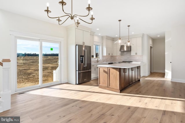 kitchen featuring high quality fridge, white cabinetry, a kitchen island, and hanging light fixtures