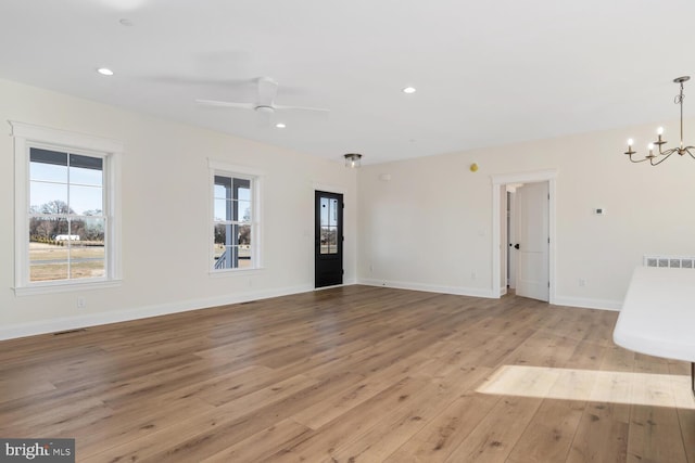 interior space featuring ceiling fan with notable chandelier and light wood-type flooring