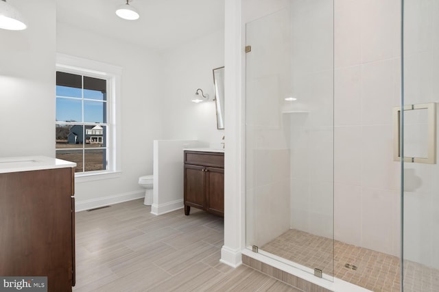 bathroom with a shower with door, vanity, and toilet