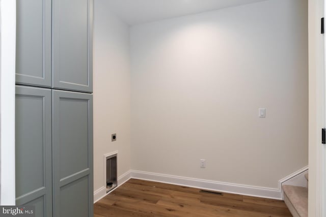 laundry room with electric dryer hookup, dark hardwood / wood-style floors, and cabinets