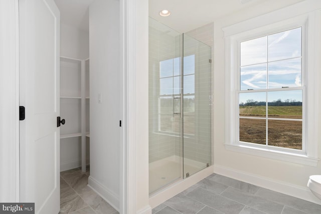 bathroom featuring a shower with shower door and toilet