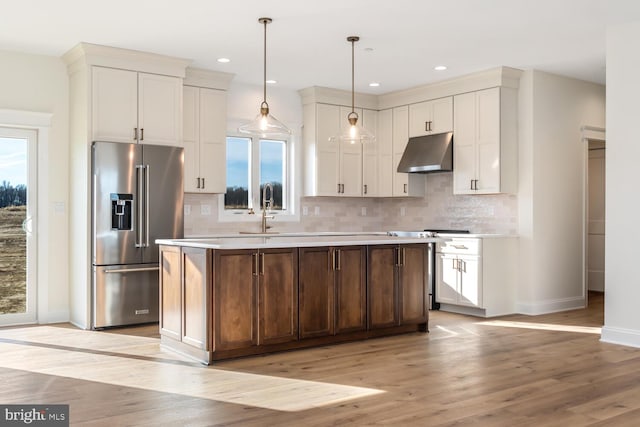 kitchen featuring a center island, light hardwood / wood-style flooring, backsplash, pendant lighting, and high end fridge