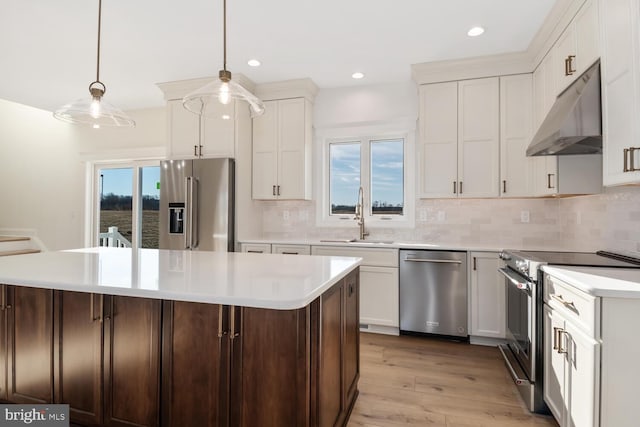 kitchen featuring appliances with stainless steel finishes, a center island, decorative light fixtures, and sink