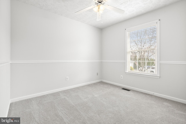 carpeted empty room featuring ceiling fan and a textured ceiling