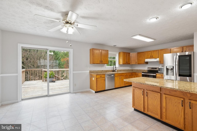 kitchen featuring light stone countertops, a textured ceiling, and appliances with stainless steel finishes